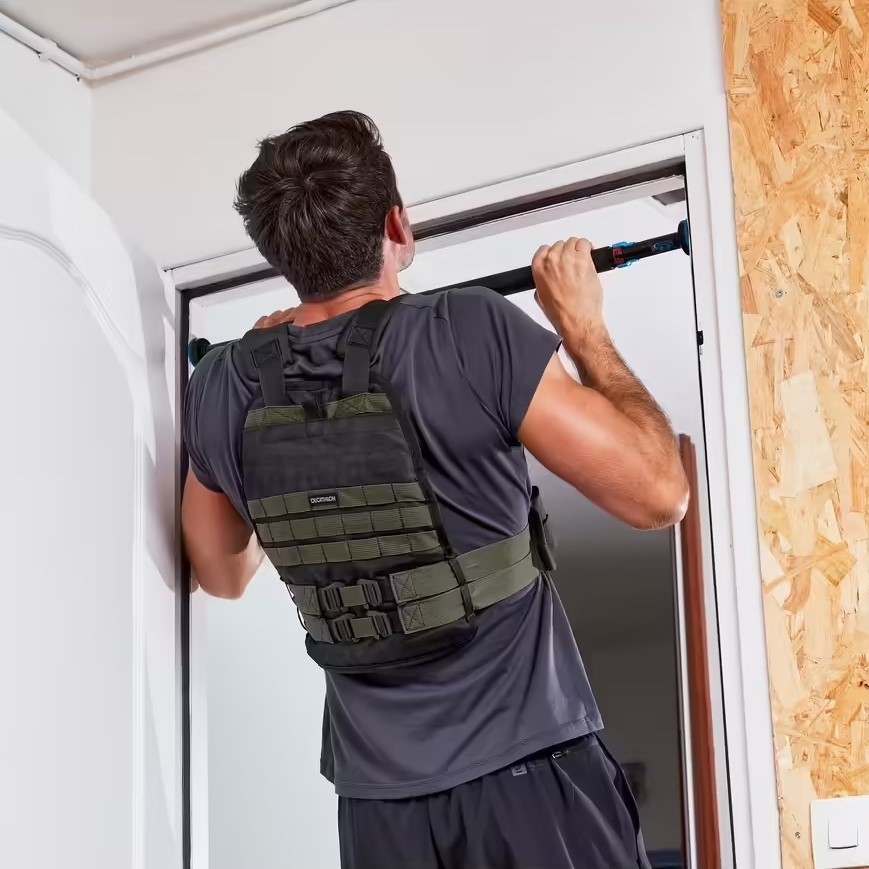 Homme portant un gilet lesté faisant des tractions sur une barres de traction pour cadres de portes