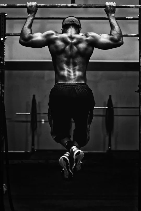 Photo en noir et blanc d'un homme faisant des tractions vue de dos