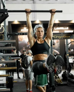 Jeune femme effectuant un L-sit jambes tendues à la barre de traction murale Kingsbox 3 seconds dans une salle de sport