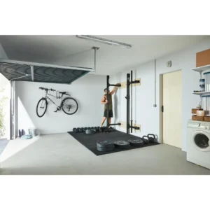 Homme mettant en place le rack mural de musculation pliable Corength decathlon dans son garage