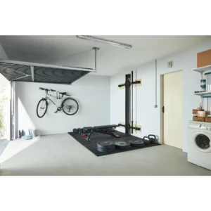 rack mural de musculation pliable Corength decathlon en position replié dans un garage avec banc de musculation et haltères